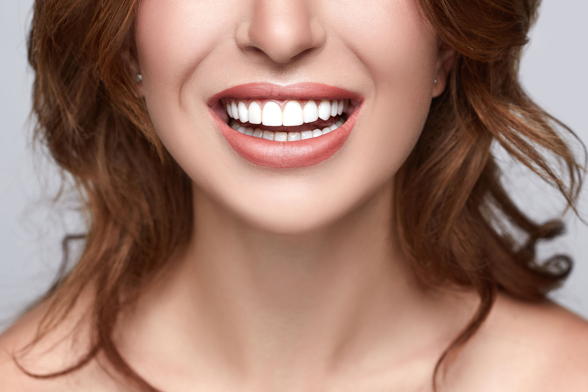 A woman with straight white teeth smiling brightly, highlighting the results of cosmetic dentistry